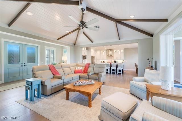 living room with vaulted ceiling with beams, ceiling fan, french doors, and light wood-type flooring