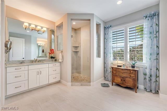 bathroom featuring tile patterned floors, vanity, walk in shower, and a chandelier