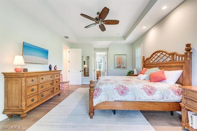 bedroom featuring ceiling fan, a raised ceiling, and wood-type flooring