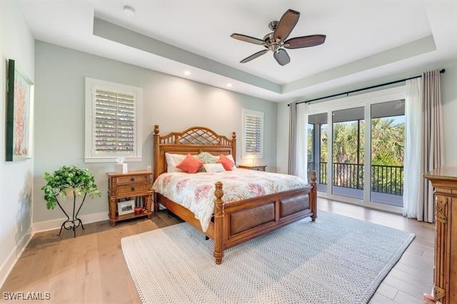 bedroom featuring a raised ceiling, ceiling fan, access to exterior, and light hardwood / wood-style flooring