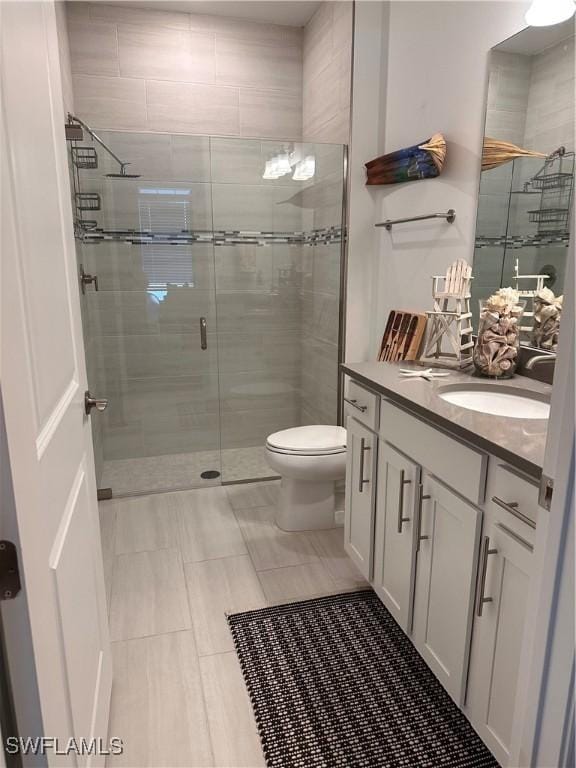 bathroom featuring tile patterned floors, toilet, vanity, and walk in shower