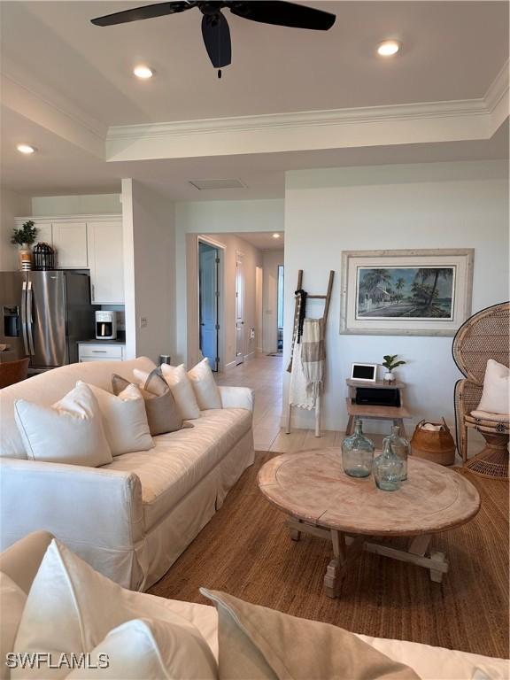 living room featuring ceiling fan, light hardwood / wood-style floors, crown molding, and a tray ceiling