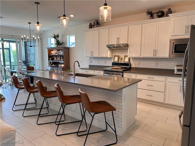 kitchen featuring hanging light fixtures, white cabinetry, a breakfast bar, and stainless steel appliances