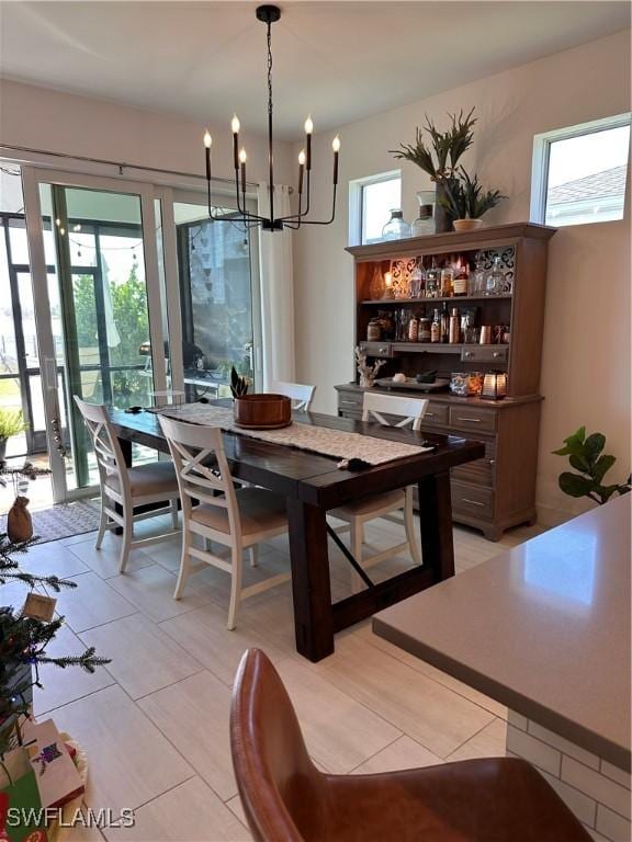 tiled dining space featuring plenty of natural light, an inviting chandelier, and french doors