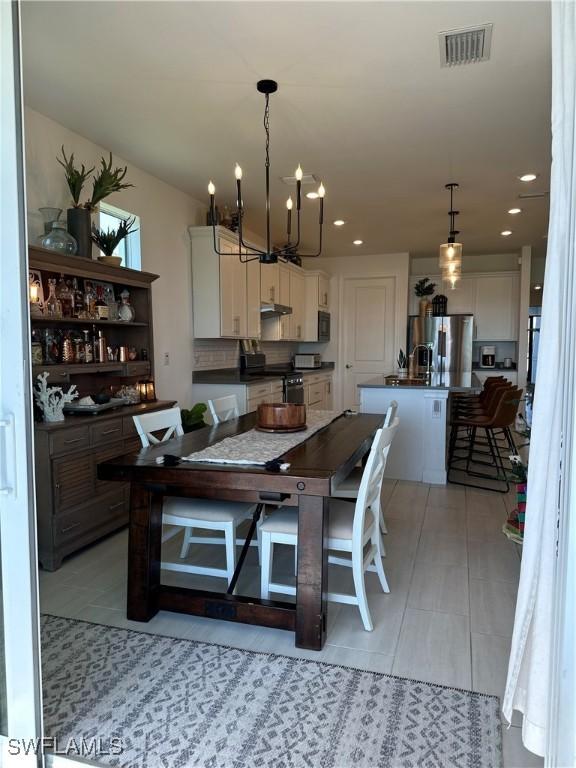 dining space with light tile patterned floors and an inviting chandelier