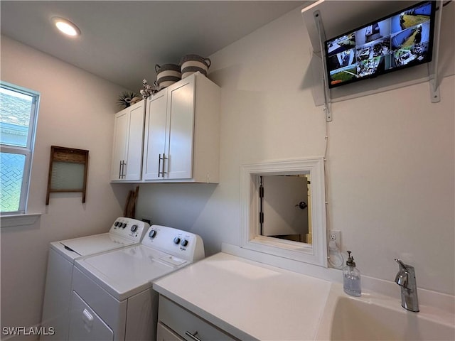 clothes washing area featuring cabinets, washing machine and dryer, and sink