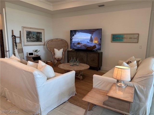 tiled living room featuring a tray ceiling and crown molding