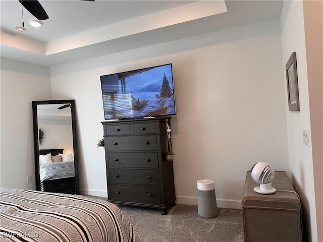 carpeted bedroom featuring ceiling fan and a tray ceiling