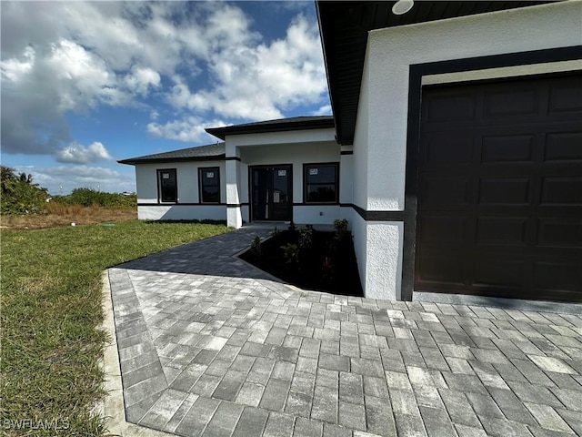 view of exterior entry with a garage and a lawn