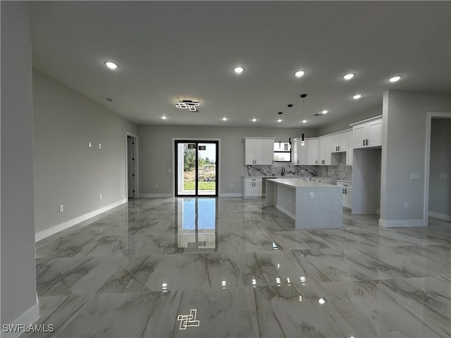 kitchen featuring backsplash, a center island, white cabinetry, and hanging light fixtures