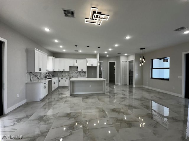 kitchen with pendant lighting, sink, decorative backsplash, a kitchen island, and white cabinetry