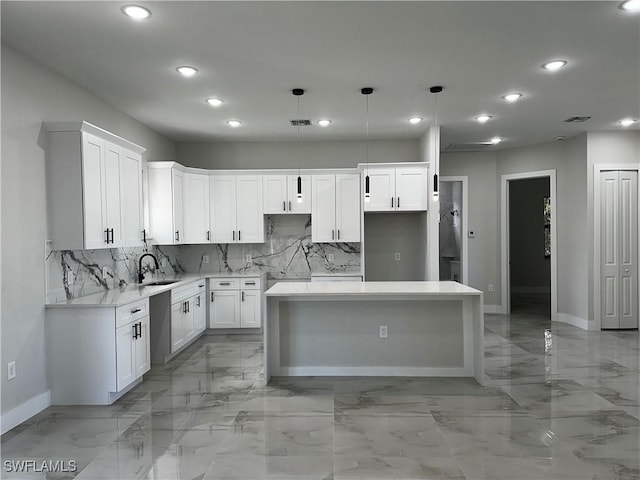 kitchen with pendant lighting, a center island, white cabinets, sink, and decorative backsplash