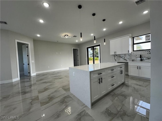 kitchen featuring backsplash, sink, decorative light fixtures, white cabinets, and a center island