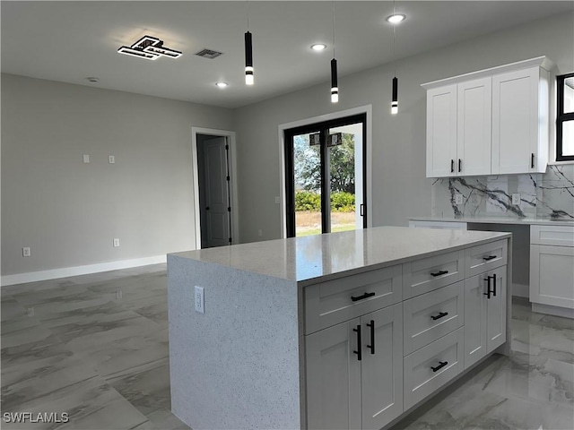 kitchen featuring pendant lighting, a center island, white cabinets, tasteful backsplash, and light stone counters