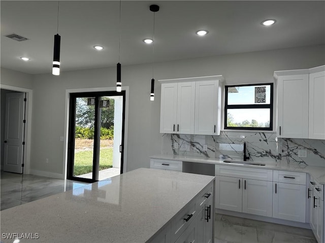 kitchen with pendant lighting, light stone counters, and white cabinetry