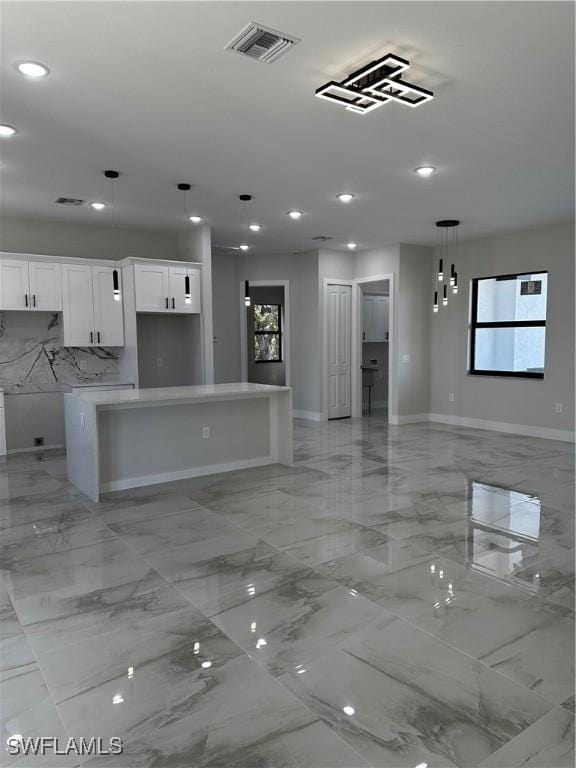 kitchen with white cabinets, decorative light fixtures, tasteful backsplash, and a kitchen island