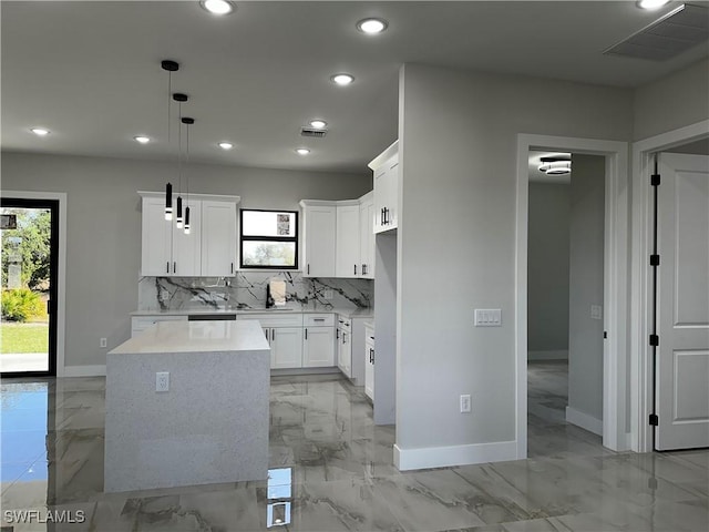 kitchen featuring white cabinets, a center island, hanging light fixtures, and tasteful backsplash