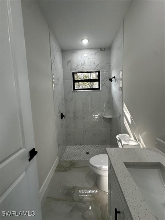 bathroom featuring tiled shower, vanity, and toilet