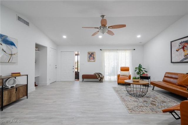 living room with ceiling fan, light hardwood / wood-style flooring, and vaulted ceiling