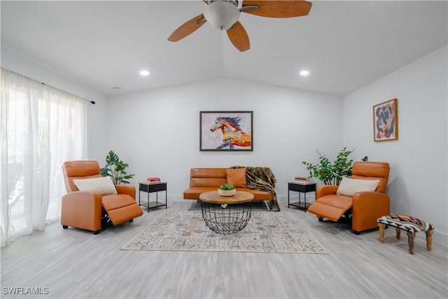 living room with ceiling fan, light hardwood / wood-style flooring, and vaulted ceiling