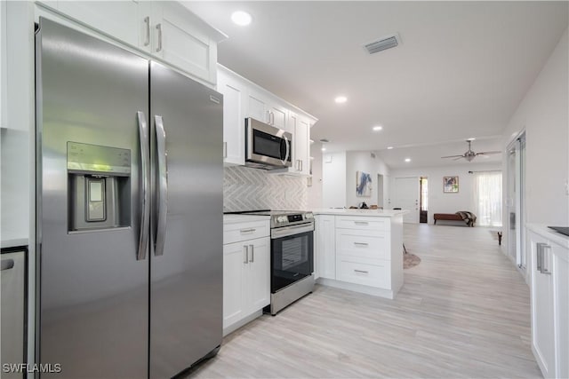 kitchen featuring white cabinets, decorative backsplash, stainless steel appliances, and kitchen peninsula