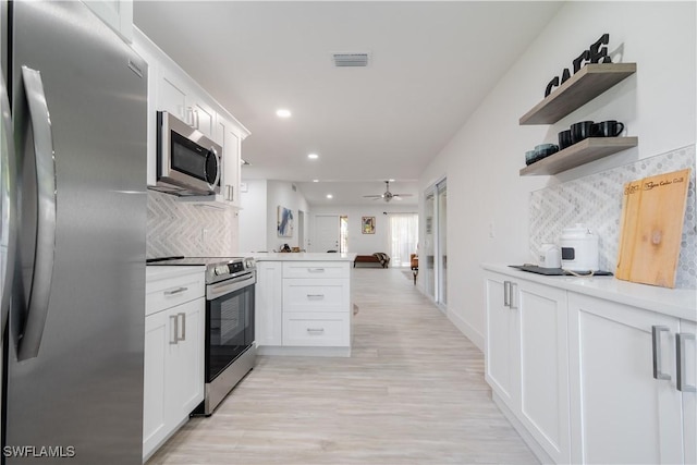 kitchen with kitchen peninsula, tasteful backsplash, stainless steel appliances, light hardwood / wood-style flooring, and white cabinets