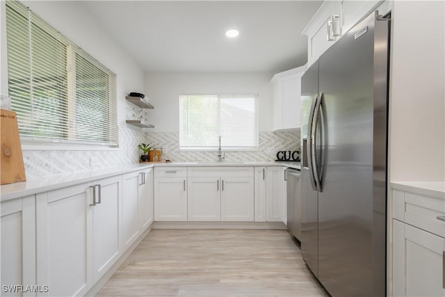 kitchen featuring white cabinets, appliances with stainless steel finishes, decorative backsplash, and sink