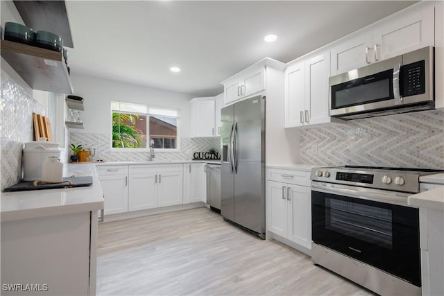 kitchen with tasteful backsplash, stainless steel appliances, sink, light hardwood / wood-style flooring, and white cabinetry