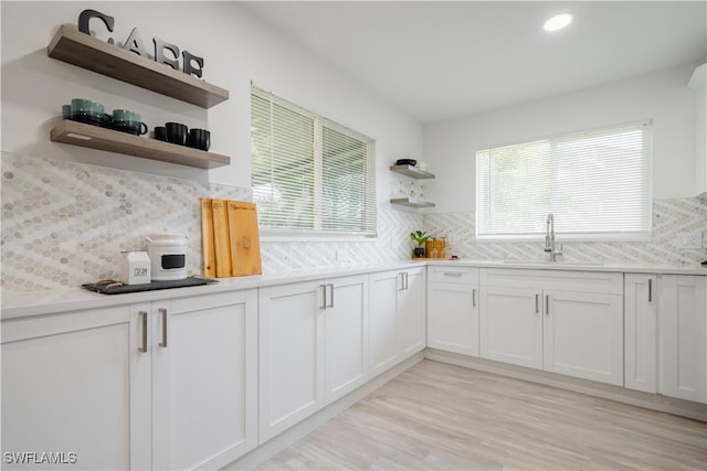 kitchen featuring white cabinets, decorative backsplash, plenty of natural light, and sink