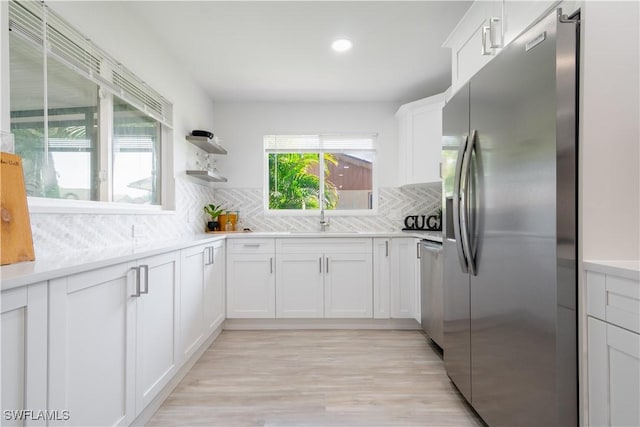 kitchen featuring white cabinets, sink, appliances with stainless steel finishes, tasteful backsplash, and light hardwood / wood-style floors