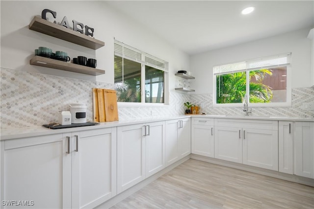 kitchen featuring backsplash, white cabinetry, plenty of natural light, and light hardwood / wood-style floors