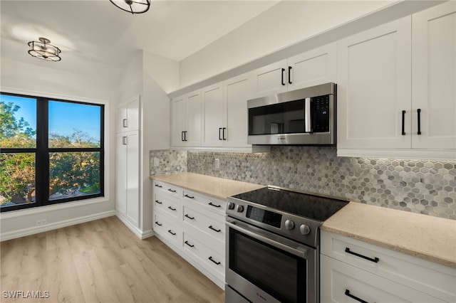 kitchen featuring white cabinetry, light stone counters, light hardwood / wood-style flooring, decorative backsplash, and appliances with stainless steel finishes