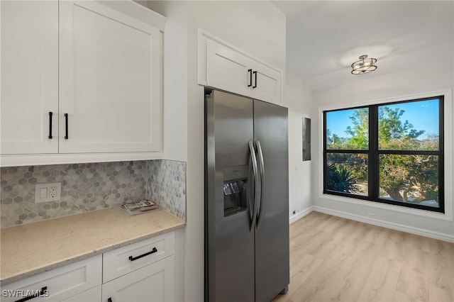 kitchen with stainless steel fridge, tasteful backsplash, white cabinetry, and light stone counters