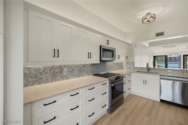 kitchen featuring tasteful backsplash, white cabinetry, sink, and appliances with stainless steel finishes