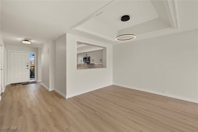 interior space featuring a tray ceiling and light hardwood / wood-style floors