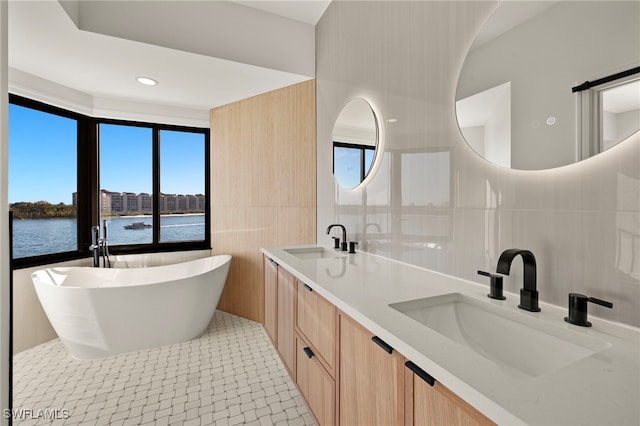 bathroom with vanity, a water view, tile patterned flooring, a washtub, and tile walls