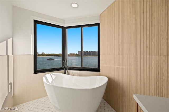 bathroom featuring tile patterned flooring, a water view, and a bathtub