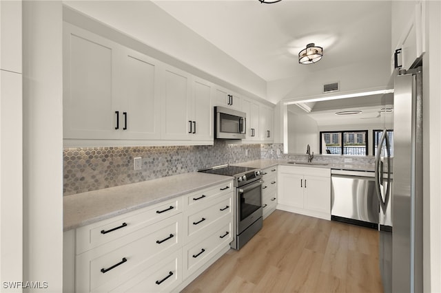 kitchen with white cabinetry, sink, light stone countertops, tasteful backsplash, and appliances with stainless steel finishes