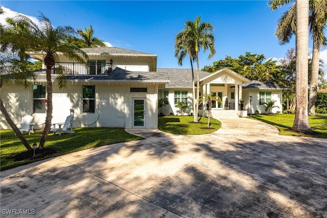 view of front of property with a balcony and a front lawn