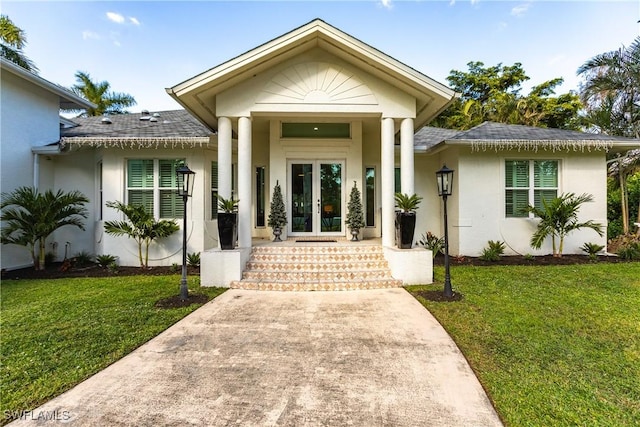 view of exterior entry featuring a lawn and french doors