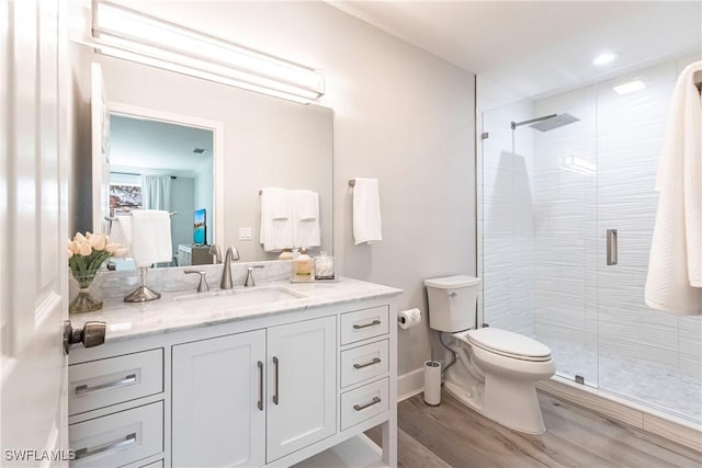 bathroom featuring vanity, hardwood / wood-style flooring, toilet, and a shower with door