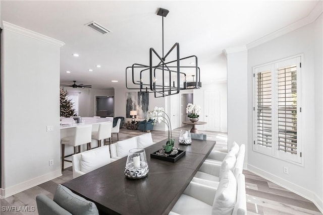 dining space with ornamental molding, ceiling fan with notable chandelier, and light wood-type flooring