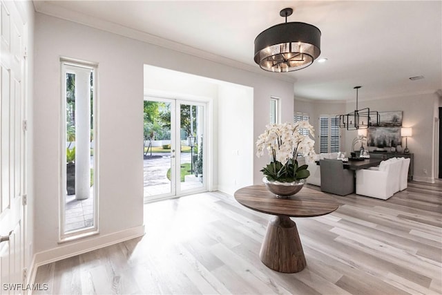 foyer entrance featuring a chandelier, french doors, light hardwood / wood-style flooring, and ornamental molding