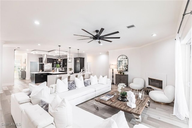 living room featuring light hardwood / wood-style flooring, ceiling fan, and ornamental molding