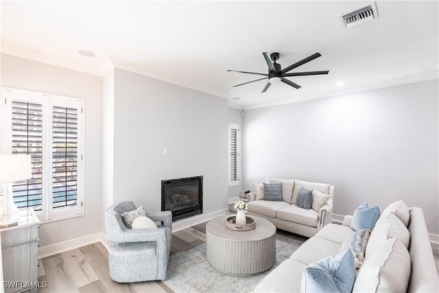 living room with ceiling fan, crown molding, and light hardwood / wood-style flooring