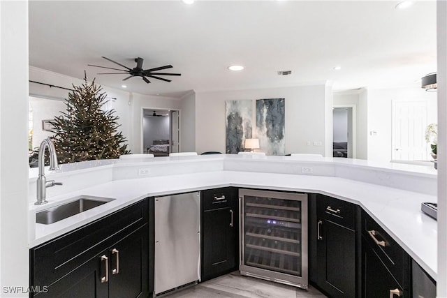 kitchen featuring sink, wine cooler, ceiling fan, light wood-type flooring, and ornamental molding