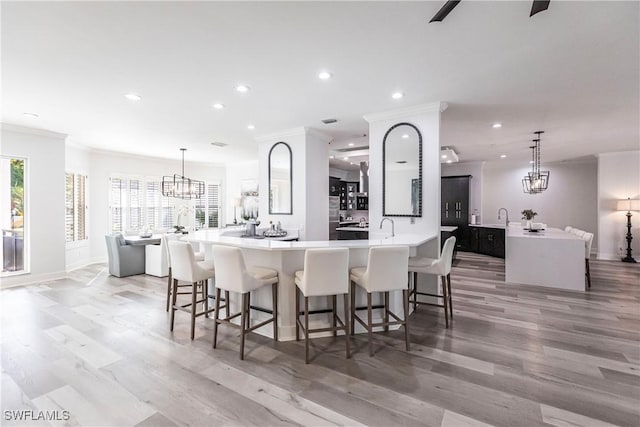 kitchen featuring light hardwood / wood-style flooring, hanging light fixtures, a large island, and crown molding