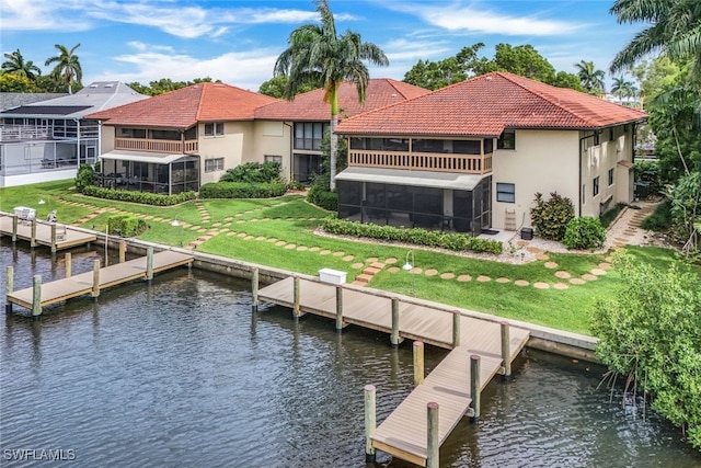 back of property with a water view and a sunroom