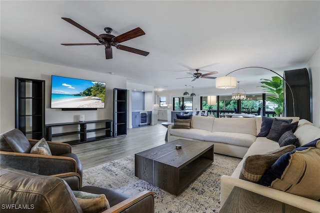 living room with ceiling fan with notable chandelier and light hardwood / wood-style floors