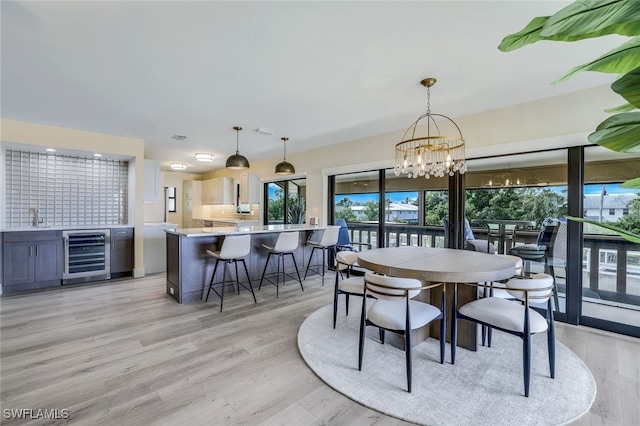 dining space featuring a chandelier, sink, wine cooler, and light hardwood / wood-style flooring